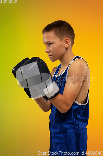 Image of Teenage boxer against gradient neon studio background in motion of kicking, boxing