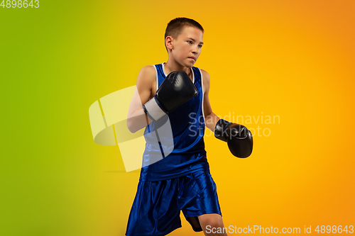 Image of Teenage boxer against gradient neon studio background in motion of kicking, boxing