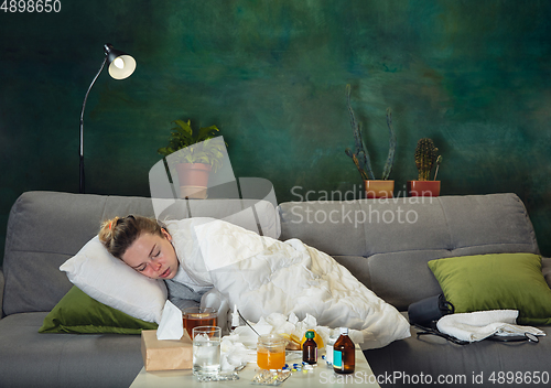 Image of Ill young girl with fever and cold looks suffering at home