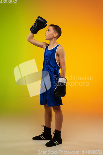 Image of Teenage boxer against gradient neon studio background in motion of kicking, boxing