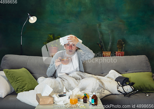 Image of Ill young girl with fever and cold looks suffering at home