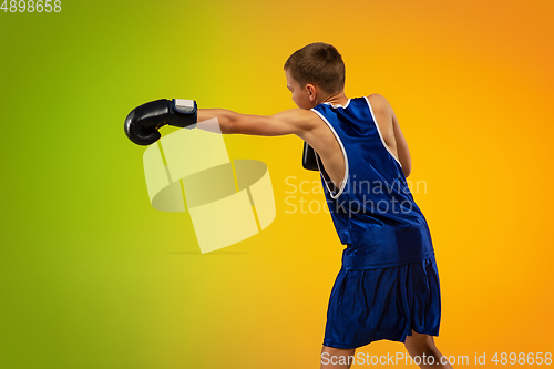 Image of Teenage boxer against gradient neon studio background in motion of kicking, boxing