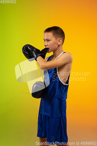 Image of Teenage boxer against gradient neon studio background in motion of kicking, boxing