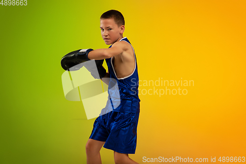 Image of Teenage boxer against gradient neon studio background in motion of kicking, boxing