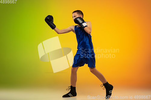 Image of Teenage boxer against gradient neon studio background in motion of kicking, boxing