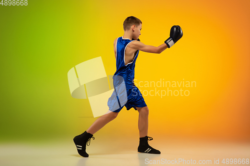 Image of Teenage boxer against gradient neon studio background in motion of kicking, boxing