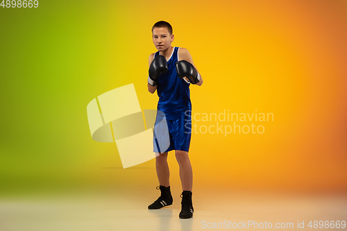 Image of Teenage boxer against gradient neon studio background in motion of kicking, boxing