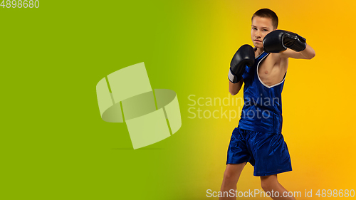 Image of Teenage boxer against gradient neon studio background in motion of kicking, boxing