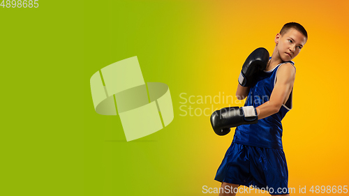 Image of Teenage boxer against gradient neon studio background in motion of kicking, boxing