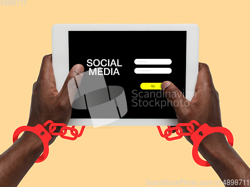 Image of Hand using tablet, device on top view. Addicted, wired with chain to social media on the screen