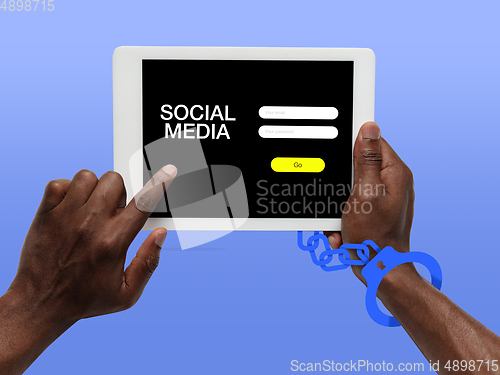 Image of Hand using tablet, device on top view. Addicted, wired with chain to social media on the screen