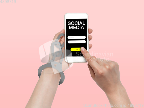 Image of Hand using smartphone, device on top view. Addicted, wired with chain to social media on the screen