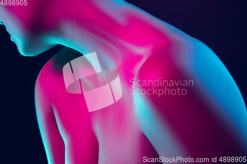 Image of Portrait of female fashion model in neon light on dark studio background.