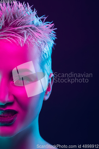 Image of Portrait of female fashion model in neon light on dark studio background.