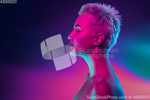 Image of Portrait of female fashion model in neon light on dark studio background.