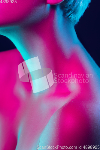 Image of Portrait of female fashion model in neon light on dark studio background.