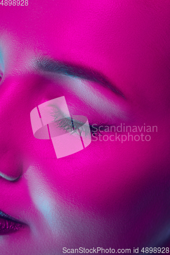 Image of Portrait of female fashion model in neon light on dark studio background.