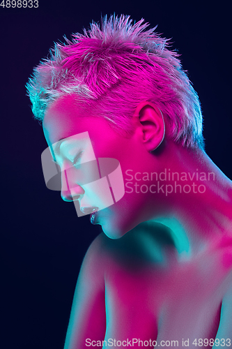 Image of Portrait of female fashion model in neon light on dark studio background.