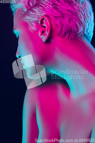 Image of Portrait of female fashion model in neon light on dark studio background.