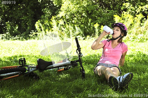 Image of Teenage girl resting in a park with a bicycle