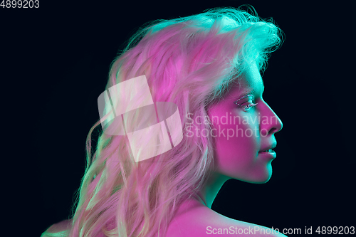 Image of Portrait of beautiful albino girl isolated on dark studio background in neon light