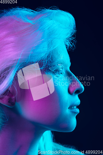 Image of Portrait of beautiful albino girl isolated on dark studio background in neon light