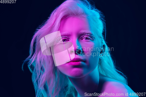 Image of Portrait of beautiful albino girl isolated on dark studio background in neon light