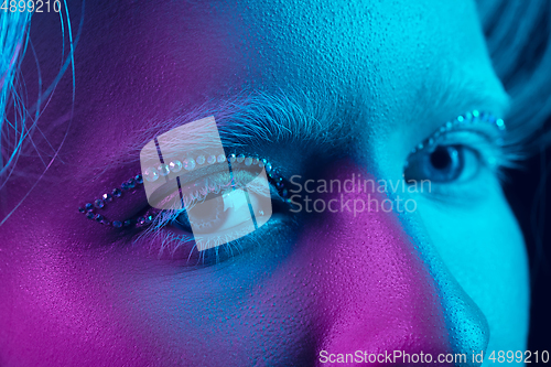 Image of Portrait of beautiful albino girl isolated on dark studio background in neon light