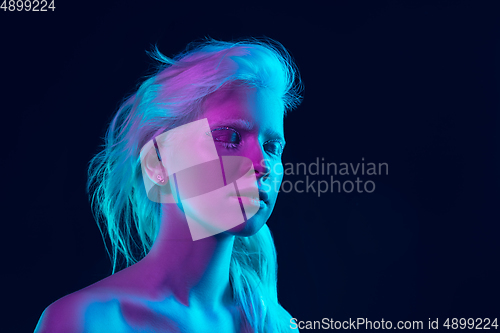 Image of Portrait of beautiful albino girl isolated on dark studio background in neon light