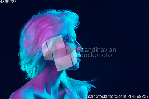 Image of Portrait of beautiful albino girl isolated on dark studio background in neon light