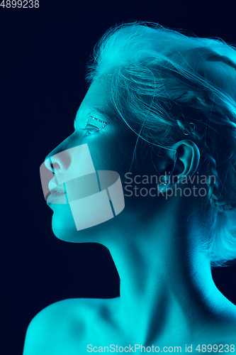 Image of Portrait of beautiful albino girl isolated on dark studio background in neon light