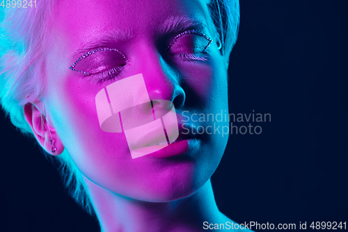 Image of Portrait of beautiful albino girl isolated on dark studio background in neon light