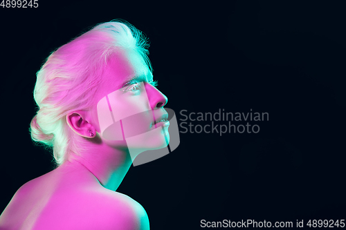 Image of Portrait of beautiful albino girl isolated on dark studio background in neon light