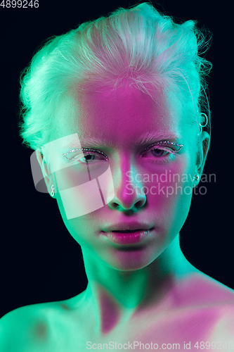 Image of Portrait of beautiful albino girl isolated on dark studio background in neon light