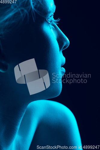 Image of Portrait of beautiful albino girl isolated on dark studio background in neon light