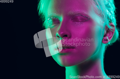 Image of Portrait of beautiful albino girl isolated on dark studio background in neon light