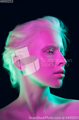 Image of Portrait of beautiful albino girl isolated on dark studio background in neon light