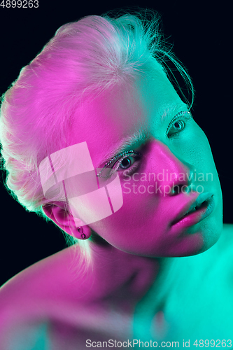 Image of Portrait of beautiful albino girl isolated on dark studio background in neon light