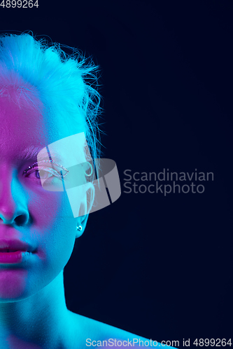 Image of Portrait of beautiful albino girl isolated on dark studio background in neon light