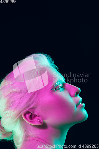 Image of Portrait of beautiful albino girl isolated on dark studio background in neon light