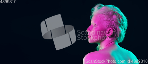 Image of Portrait of beautiful albino girl isolated on dark studio background in neon light