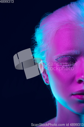 Image of Portrait of beautiful albino girl isolated on dark studio background in neon light