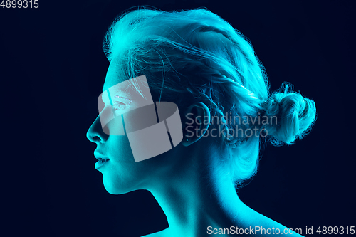 Image of Portrait of beautiful albino girl isolated on dark studio background in neon light