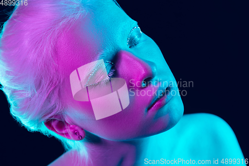 Image of Portrait of beautiful albino girl isolated on dark studio background in neon light