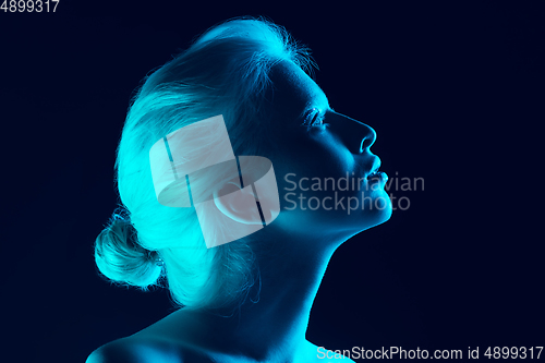 Image of Portrait of beautiful albino girl isolated on dark studio background in neon light