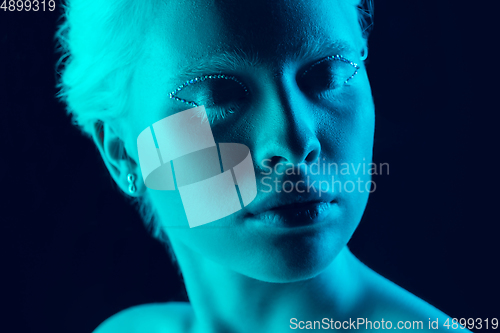 Image of Portrait of beautiful albino girl isolated on dark studio background in neon light