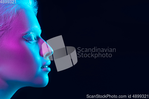 Image of Portrait of beautiful albino girl isolated on dark studio background in neon light