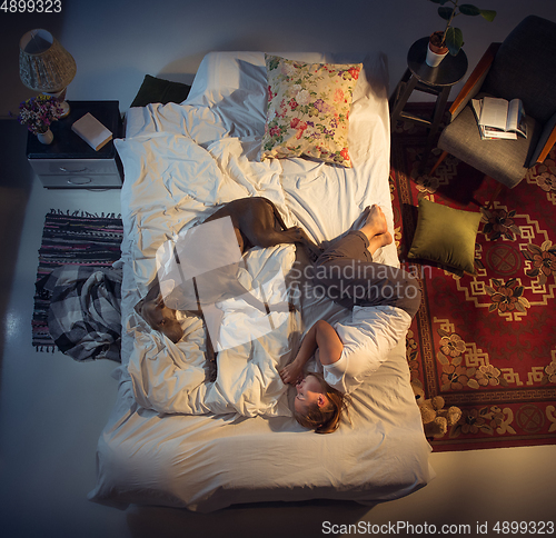 Image of Portrait of a woman, female breeder sleeping in the bed with her dog at home