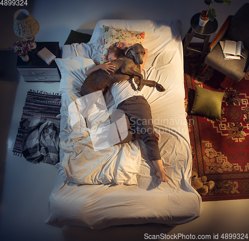 Image of Portrait of a woman, female breeder sleeping in the bed with her dog at home