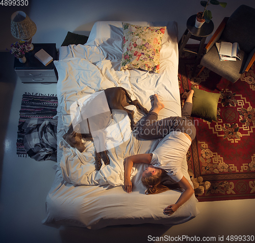 Image of Portrait of a woman, female breeder sleeping in the bed with her dog at home